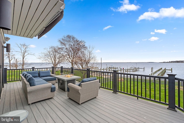 wooden deck with a water view, a dock, a lawn, and an outdoor living space with a fire pit