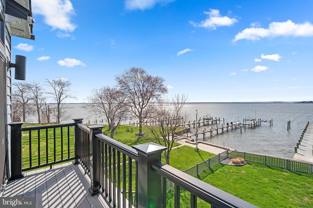 wooden terrace with a water view, a lawn, and a boat dock