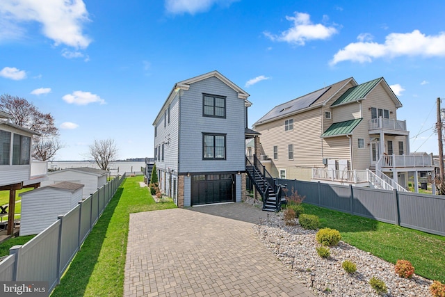 exterior space featuring an attached garage, stairs, fence, decorative driveway, and a yard