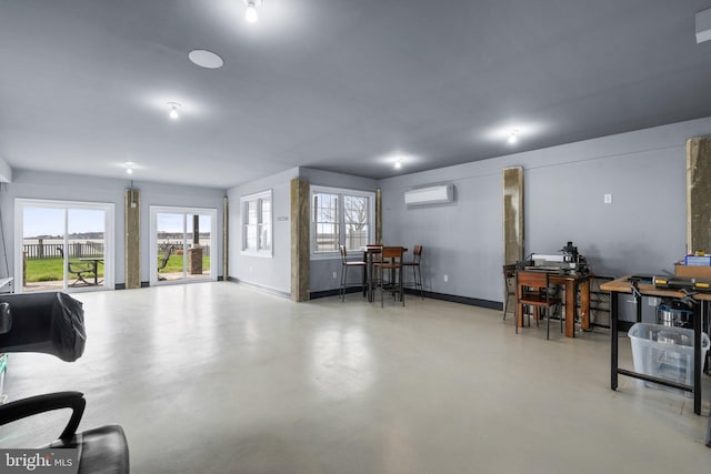 miscellaneous room featuring concrete floors, a wall mounted AC, and baseboards