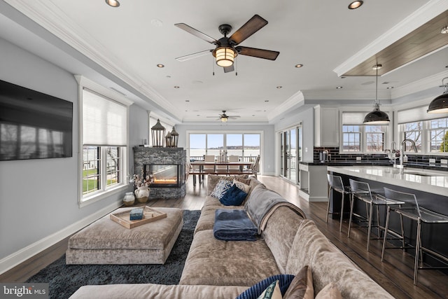 living area with dark wood-type flooring, recessed lighting, ornamental molding, and baseboards