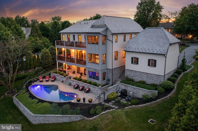 rear view of house featuring fence private yard, a balcony, a lawn, a patio area, and a high end roof