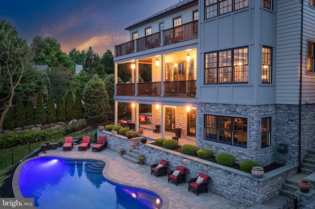 rear view of property with a fenced in pool, a patio, and a balcony