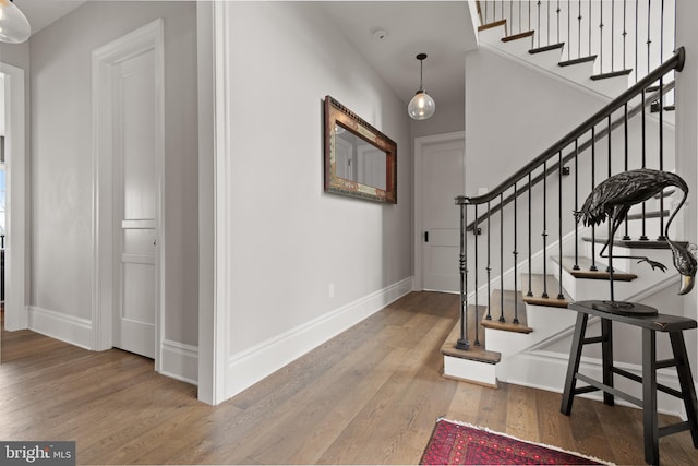 foyer entrance featuring stairway, wood finished floors, and baseboards