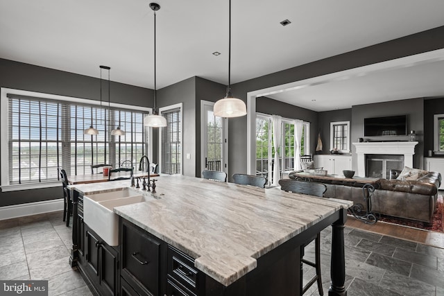 kitchen featuring dark cabinetry, a breakfast bar area, a sink, and pendant lighting