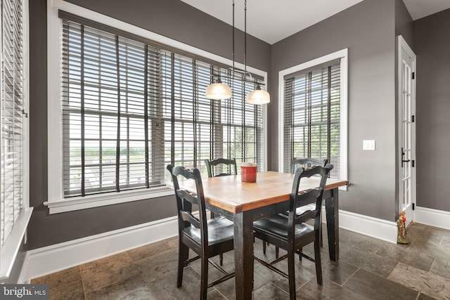 dining space with a healthy amount of sunlight, stone tile floors, and baseboards