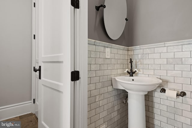 half bathroom featuring a wainscoted wall and tile walls