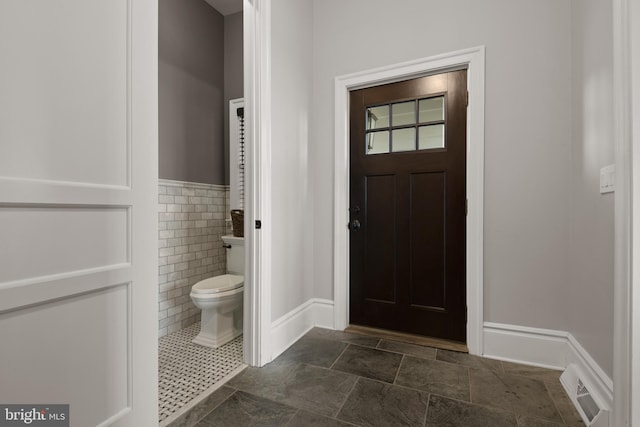 foyer entrance featuring wainscoting, visible vents, and tile walls