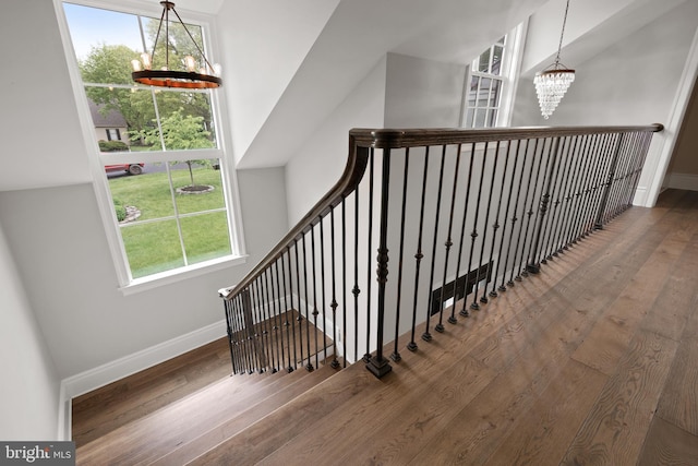 stairs with a chandelier, hardwood / wood-style floors, and baseboards