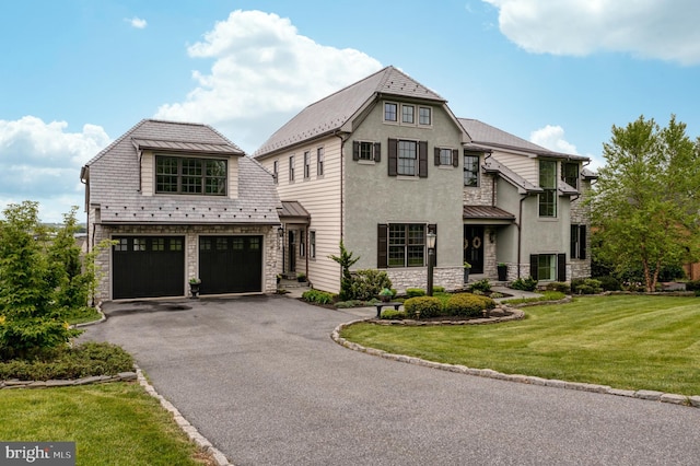 view of front facade with stone siding, aphalt driveway, metal roof, a standing seam roof, and a front lawn