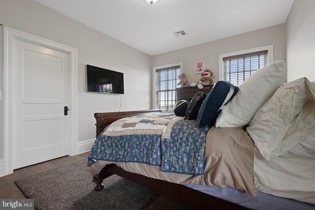 bedroom with dark wood-style floors, visible vents, and baseboards