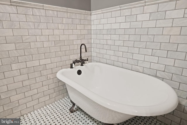 full bath with tile patterned flooring, a freestanding bath, and tile walls