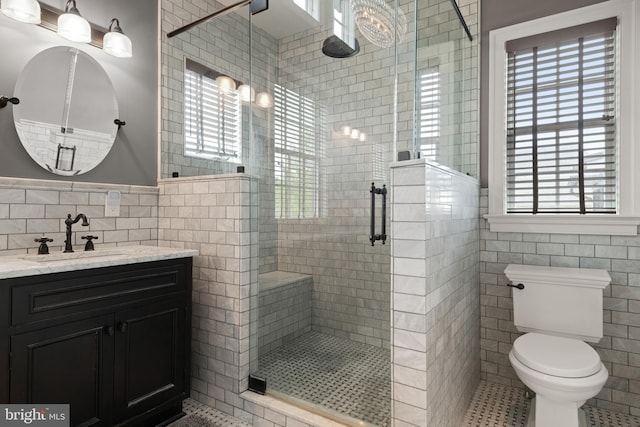 full bath featuring a stall shower, tile walls, toilet, and vanity