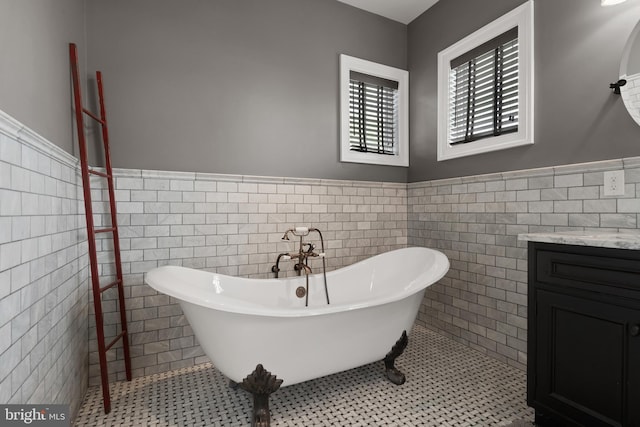 bathroom featuring a freestanding tub, wainscoting, tile walls, and tile patterned floors