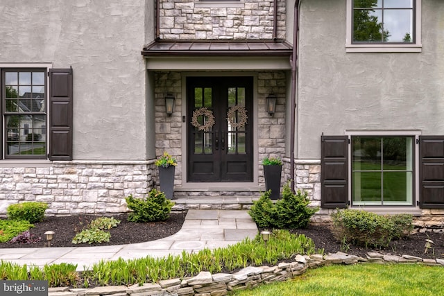 property entrance featuring stone siding, a standing seam roof, metal roof, and stucco siding