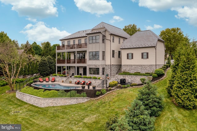 back of house with a balcony, stone siding, cooling unit, and a yard