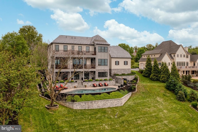 rear view of property featuring stone siding, a yard, and a balcony