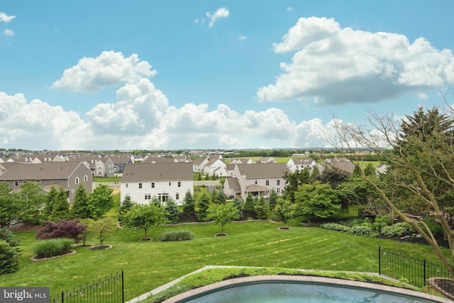 view of swimming pool featuring a lawn, fence, and a residential view