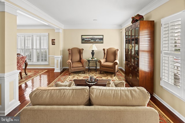 sitting room featuring a wainscoted wall, crown molding, a decorative wall, wood finished floors, and ornate columns