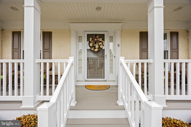 view of exterior entry featuring a porch and stucco siding