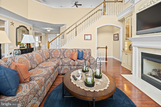 living area with built in features, baseboards, a fireplace with flush hearth, stairway, and wood finished floors