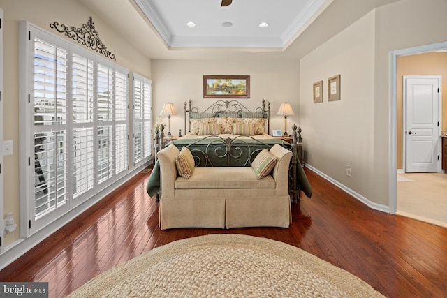 bedroom featuring a raised ceiling, crown molding, baseboards, and hardwood / wood-style flooring