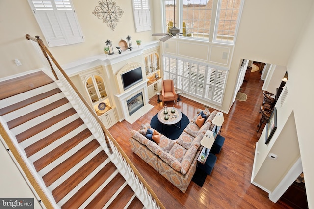 living area with a fireplace with flush hearth, a towering ceiling, wood finished floors, and visible vents