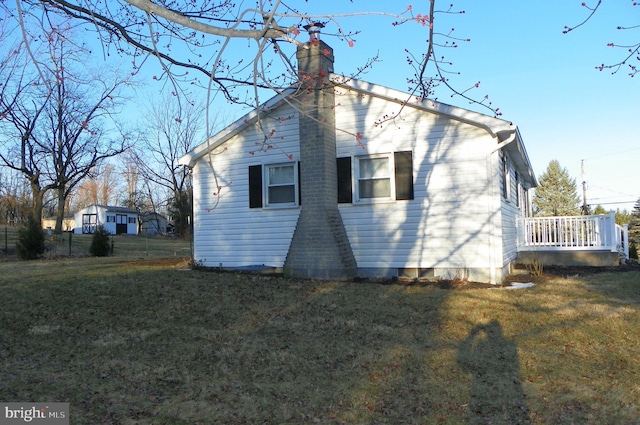 rear view of property featuring a lawn and a chimney