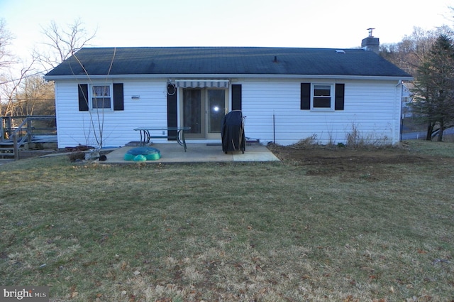 back of property with a yard, a patio, and a chimney