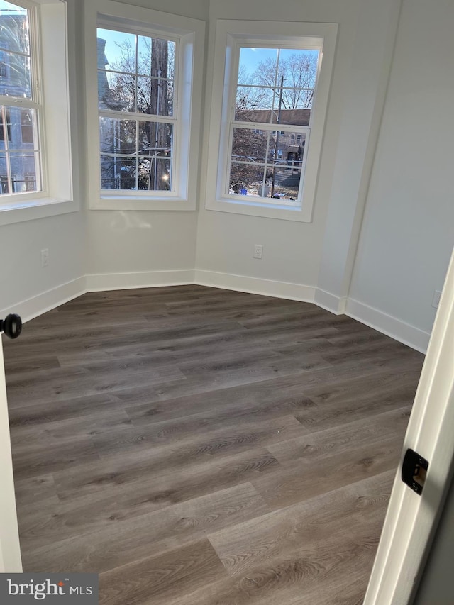 empty room featuring baseboards and dark wood-style flooring