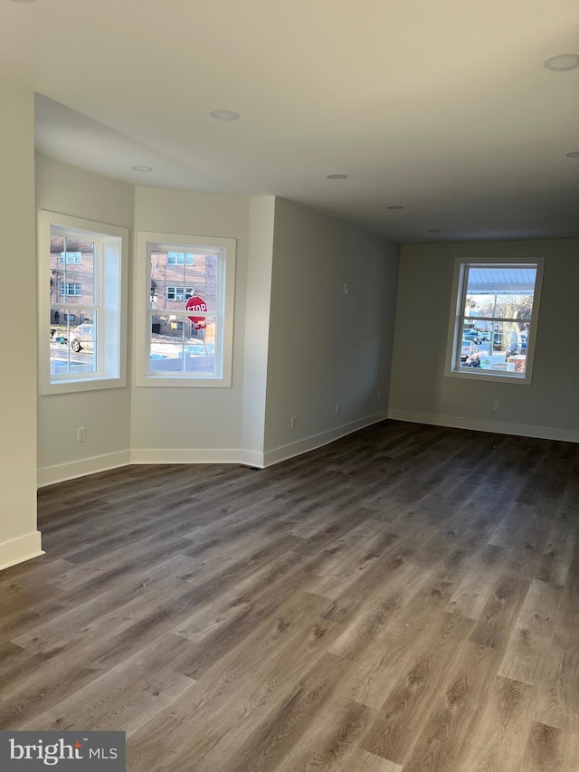 spare room with baseboards and wood finished floors