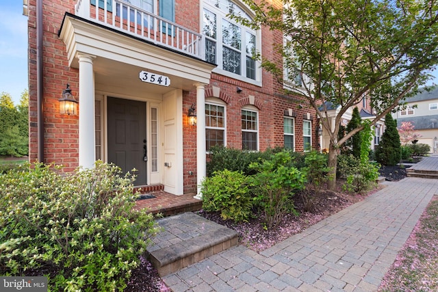 doorway to property featuring a balcony and brick siding