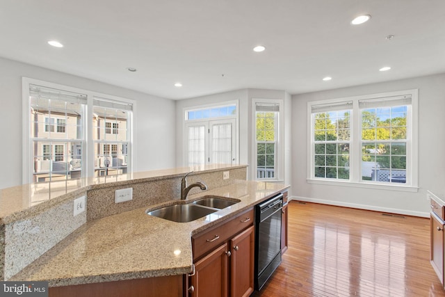 kitchen with light stone countertops, dishwasher, light wood-type flooring, and a sink