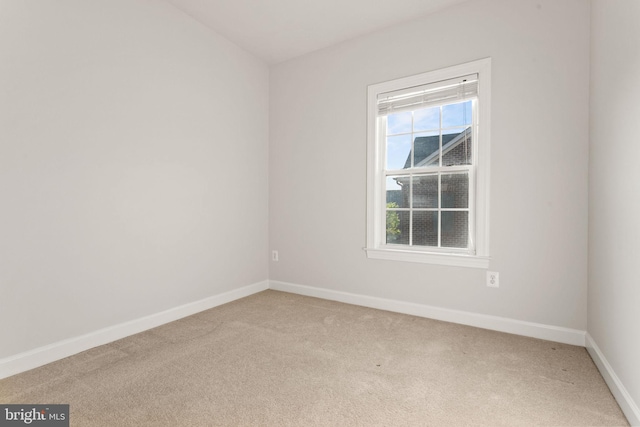 spare room featuring light carpet and baseboards