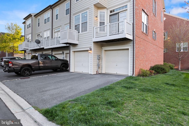 exterior space featuring a garage, a yard, driveway, and brick siding