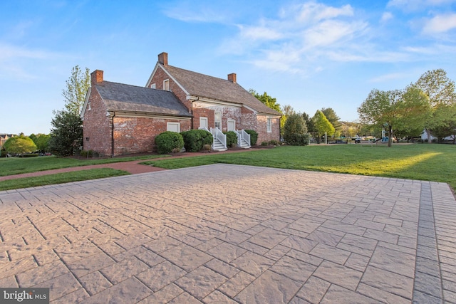 view of front of property with a front yard, brick siding, and a chimney