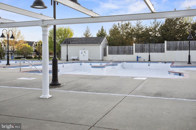 community pool featuring a patio, a hot tub, and fence