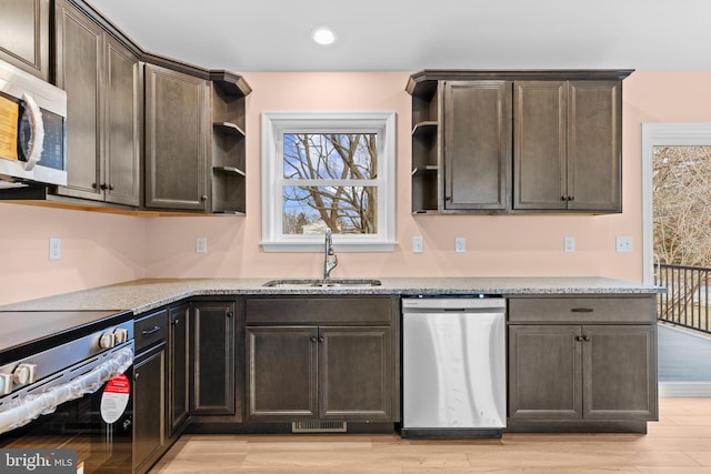 kitchen with appliances with stainless steel finishes, light stone countertops, light wood-style floors, open shelves, and a sink