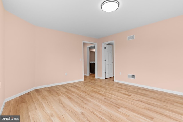 unfurnished room with light wood-style flooring, visible vents, and baseboards