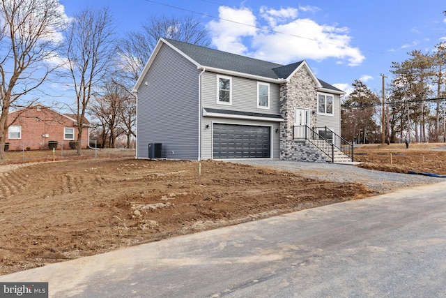 view of front of home with roof with shingles, central air condition unit, a garage, stone siding, and driveway