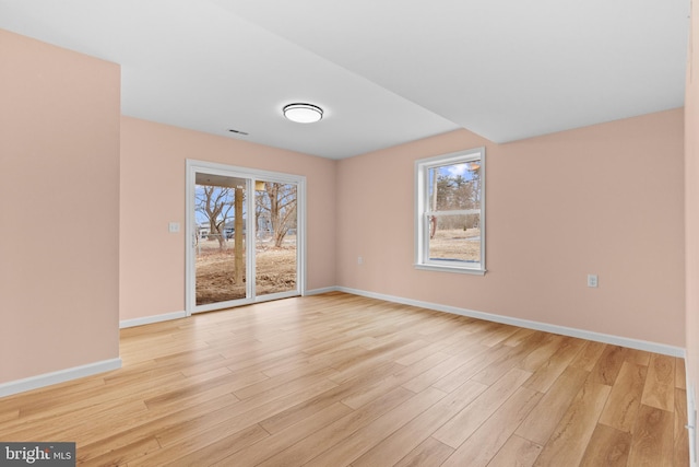 unfurnished room featuring visible vents, light wood-style flooring, and baseboards