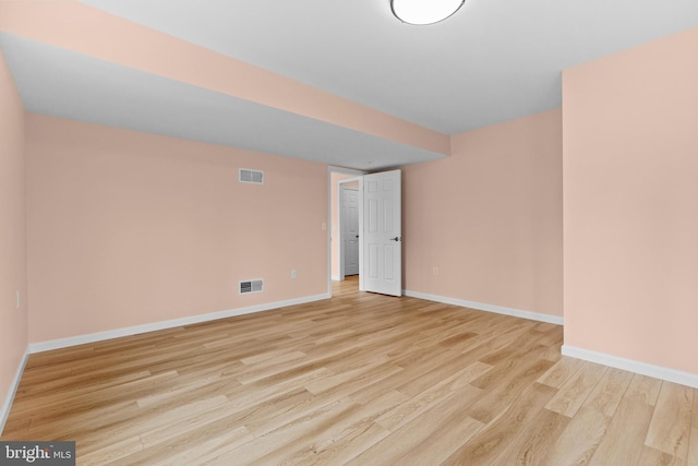 unfurnished room featuring light wood finished floors, visible vents, and baseboards