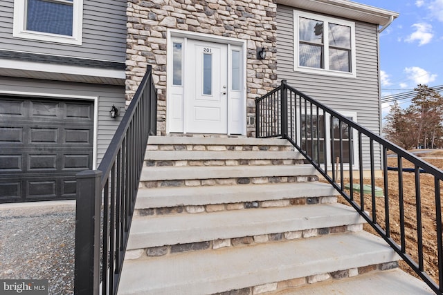 view of exterior entry with an attached garage and stone siding