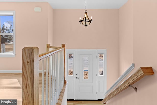 entrance foyer featuring baseboards, wood finished floors, and a notable chandelier