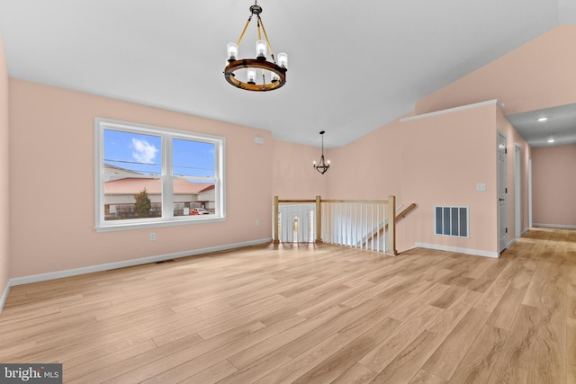 spare room featuring baseboards, light wood-style flooring, visible vents, and a notable chandelier