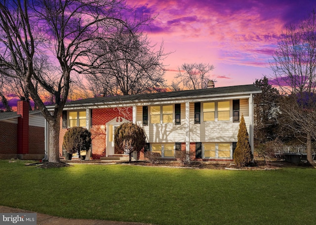 split foyer home with a front yard, a chimney, and brick siding