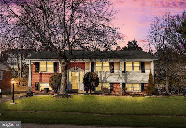 split foyer home featuring a lawn and brick siding