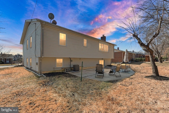 back of house featuring a chimney, cooling unit, and a patio