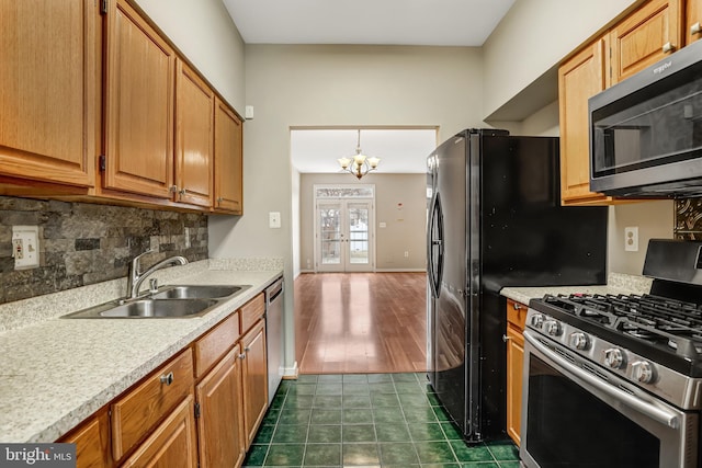 kitchen with light countertops, backsplash, appliances with stainless steel finishes, a sink, and dark tile patterned flooring