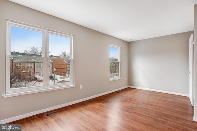 unfurnished room with wood finished floors, visible vents, and baseboards